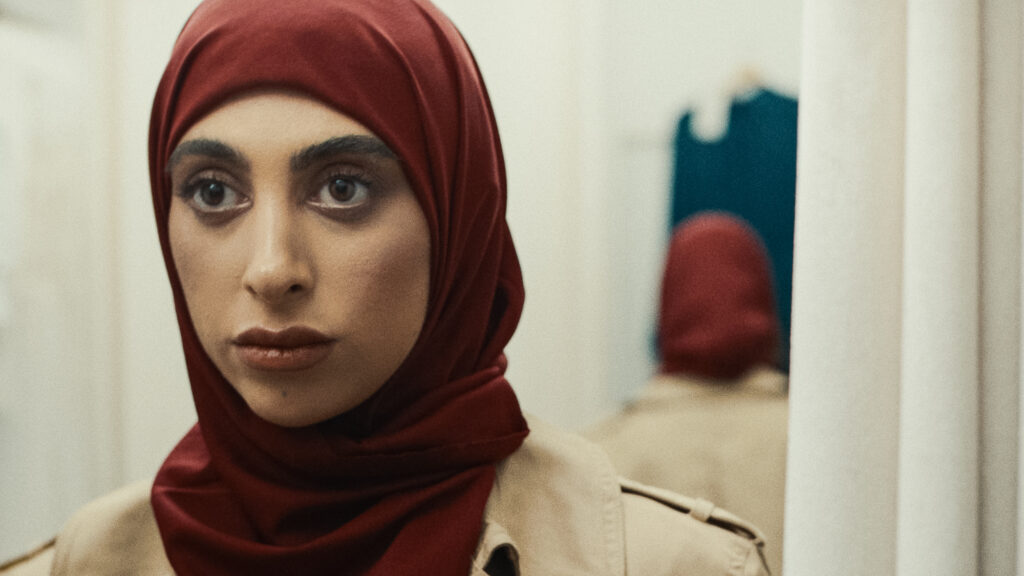 Woman in red headscarf looking toward camera, interior shop setting