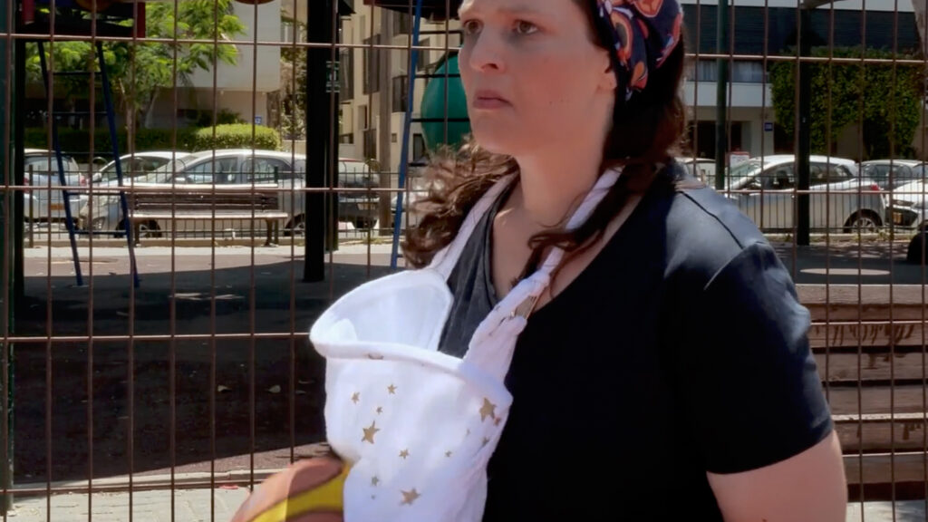 Woman standing on outdoor basketball court holding a ball, daytime