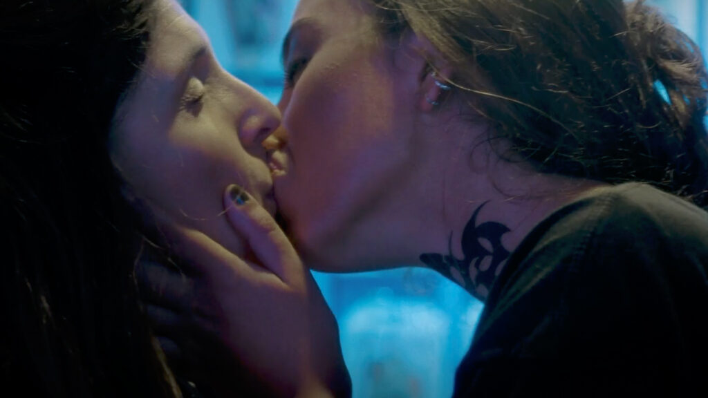 Two women in close physical interaction inside neon-lit shop