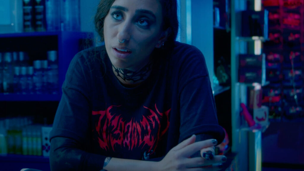Woman leaning forward on shop counter under blue and pink neon lighting