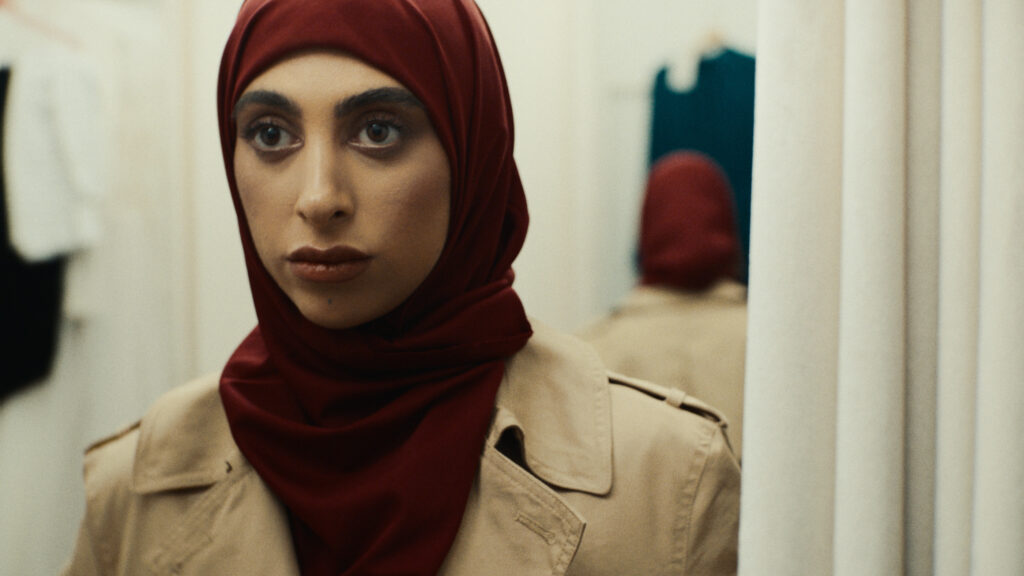 Lima, a Palestinian woman, in a camel coat in a clothing store fitting room. Still from The Camel Coat, a short film by Yochi Feinerman.